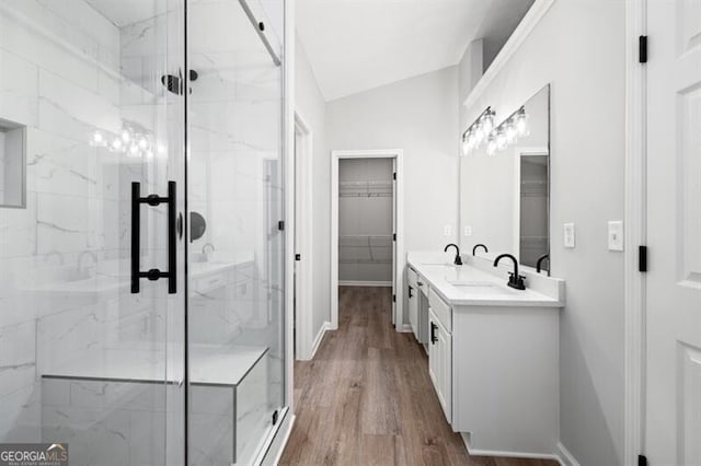 bathroom featuring hardwood / wood-style flooring, vanity, a shower with shower door, and vaulted ceiling