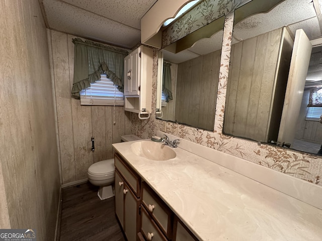 bathroom featuring vanity, a textured ceiling, wooden walls, hardwood / wood-style floors, and toilet