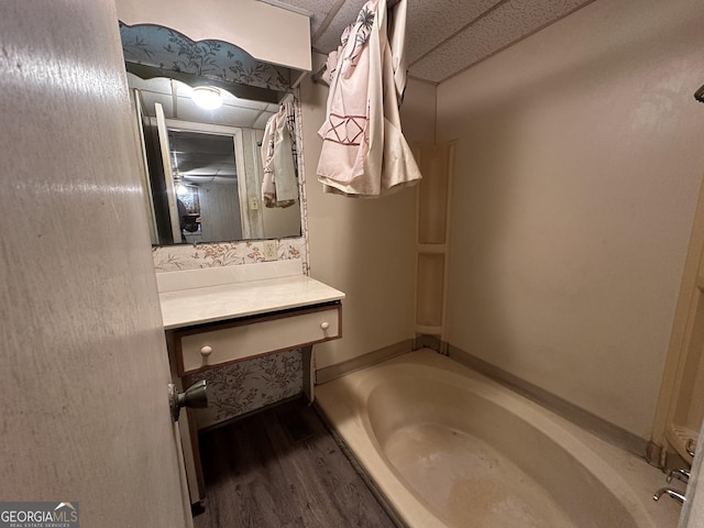 bathroom with a bath, vanity, and wood-type flooring