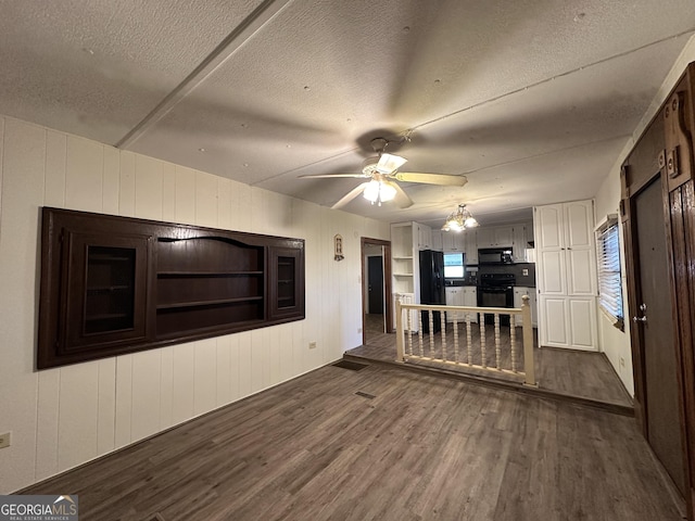 unfurnished living room with a textured ceiling, ceiling fan, and dark wood-type flooring