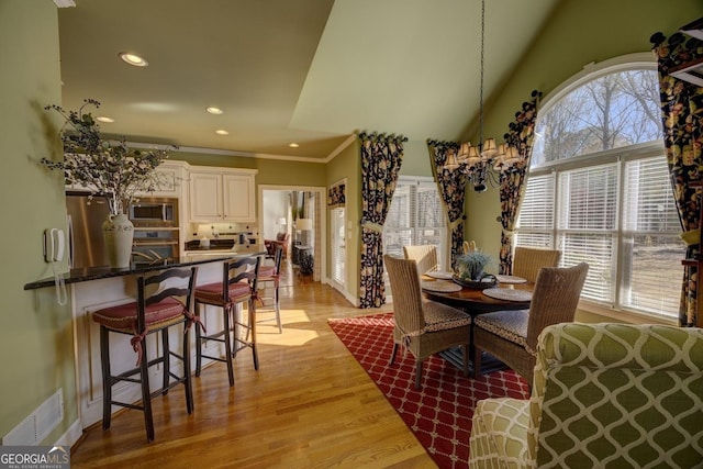 dining room with light hardwood / wood-style floors, lofted ceiling, crown molding, and a wealth of natural light