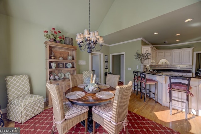 dining room with a chandelier, light wood-type flooring, crown molding, and vaulted ceiling