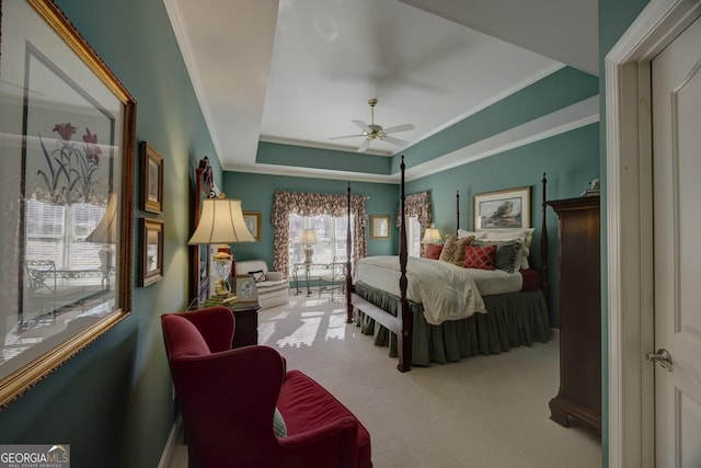 bedroom featuring carpet flooring, ceiling fan, ornamental molding, and a tray ceiling