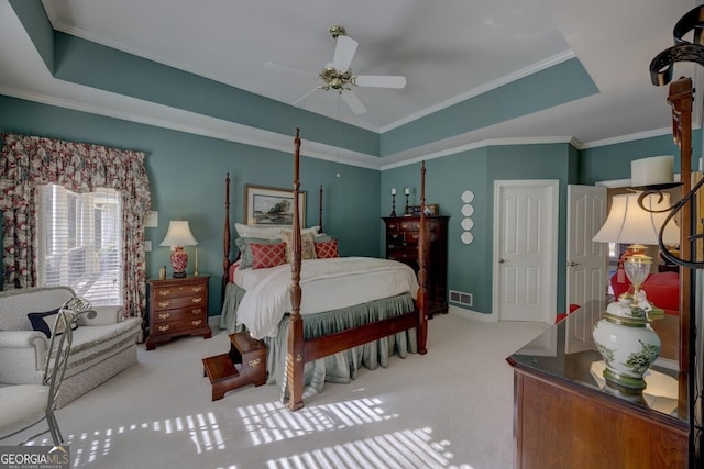 carpeted bedroom with ceiling fan, a raised ceiling, and crown molding