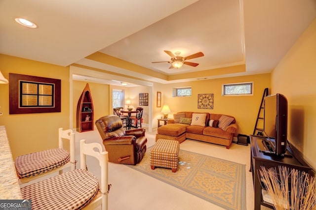 living room with carpet flooring, ceiling fan, and a tray ceiling