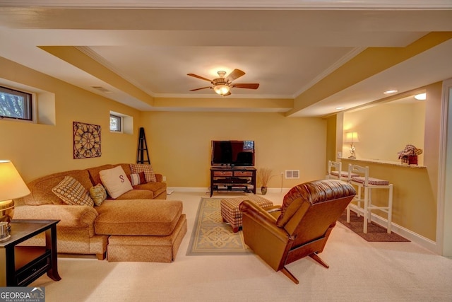 living room with ceiling fan, a raised ceiling, crown molding, and light carpet