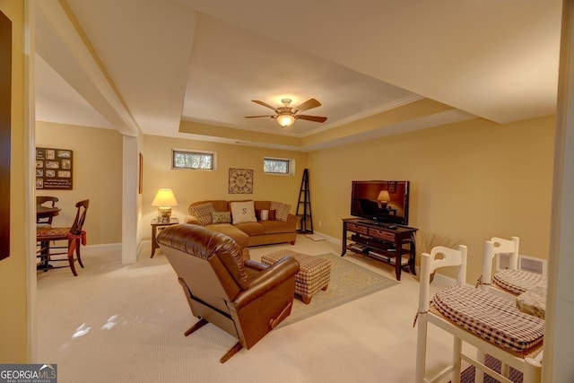 carpeted living room featuring ceiling fan, a raised ceiling, and ornamental molding