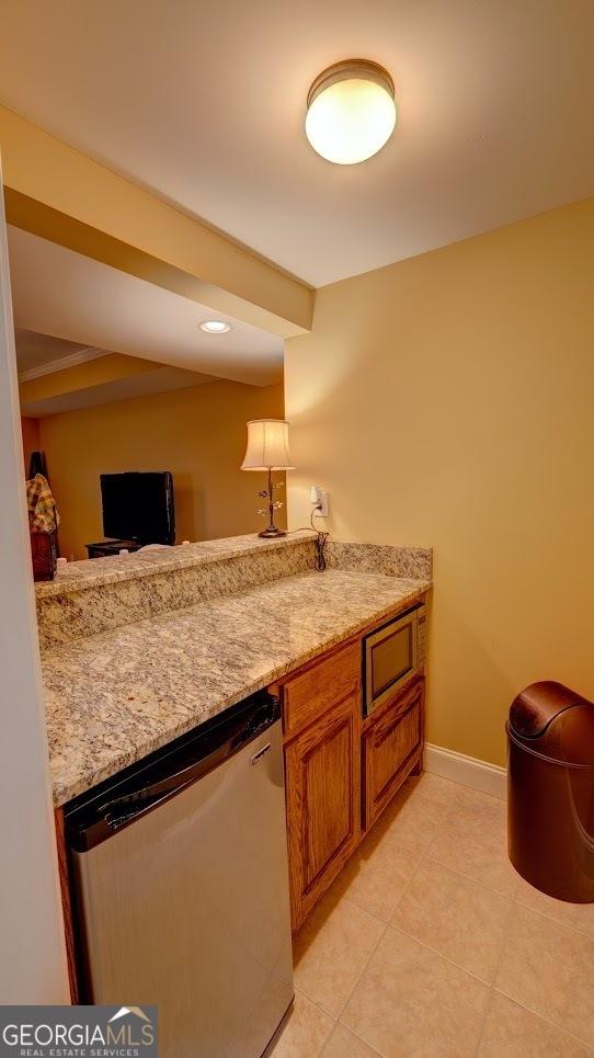 kitchen featuring dishwasher, light stone counters, and light tile patterned floors