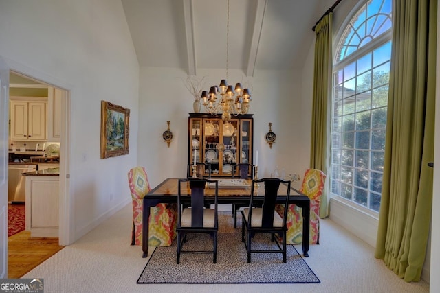 carpeted dining space featuring lofted ceiling with beams and a chandelier