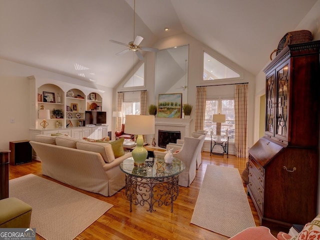 living room featuring ceiling fan, built in features, lofted ceiling, and light wood-type flooring