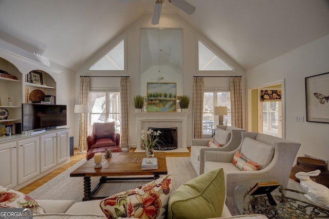 living room featuring ceiling fan, light wood-type flooring, built in features, and vaulted ceiling