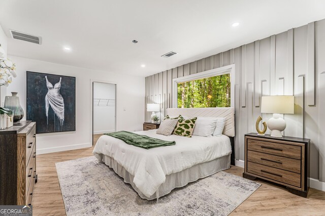 bedroom with light hardwood / wood-style floors, a spacious closet, and a closet