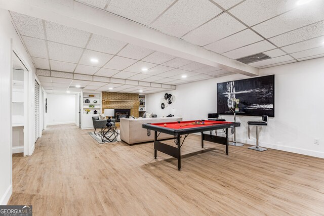 playroom featuring a fireplace, hardwood / wood-style floors, a paneled ceiling, and built in features