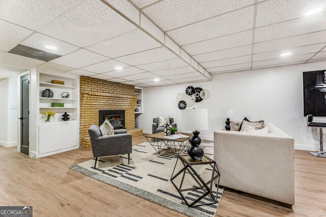 living room featuring a paneled ceiling, wood-type flooring, and built in features