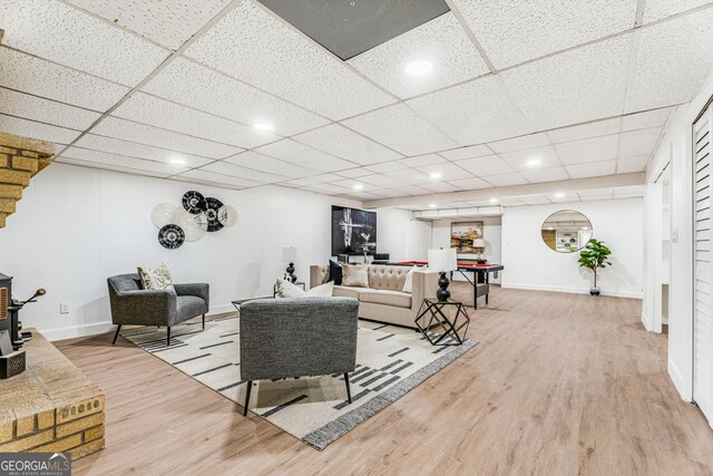 living room featuring a drop ceiling and light wood-type flooring