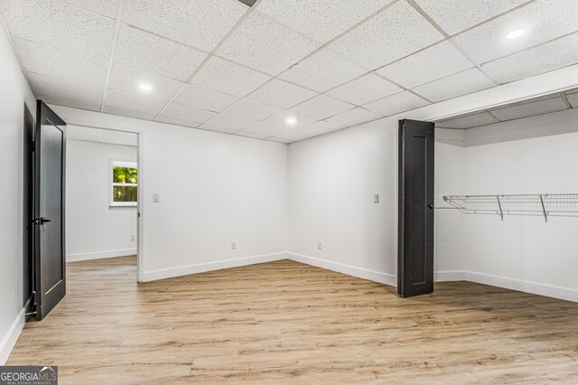 unfurnished bedroom with a drop ceiling and light hardwood / wood-style floors