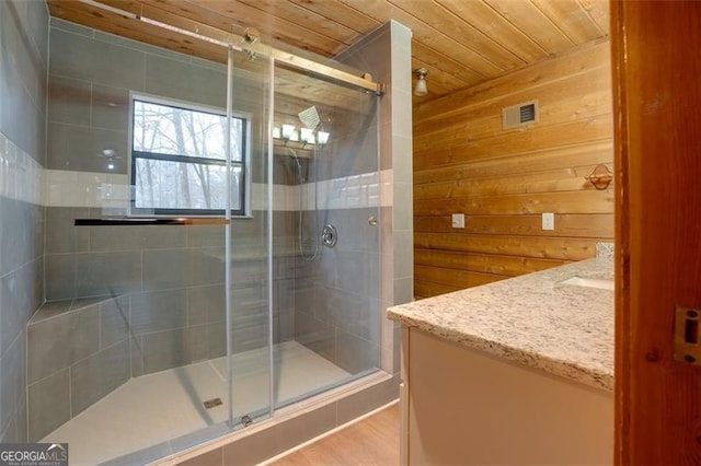 bathroom with vanity, walk in shower, wooden walls, and wood ceiling