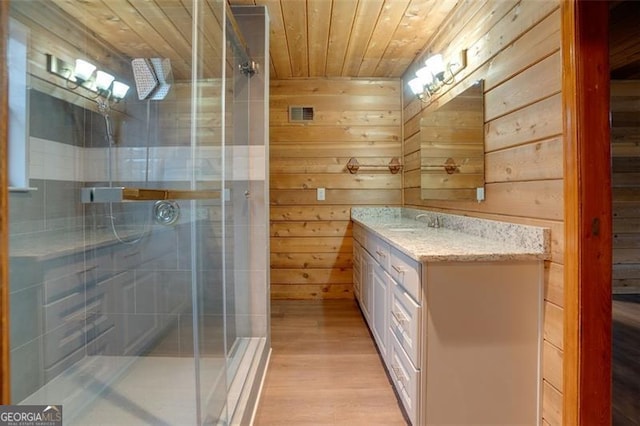 bathroom with vanity, wooden ceiling, a shower with door, wooden walls, and wood-type flooring