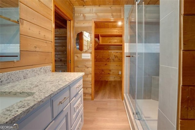 bathroom featuring wood walls, vanity, wooden ceiling, and walk in shower