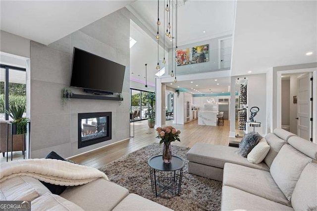 living room with a fireplace, a high ceiling, and light hardwood / wood-style flooring