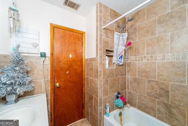 bathroom featuring sink, a textured ceiling, and tiled shower / bath