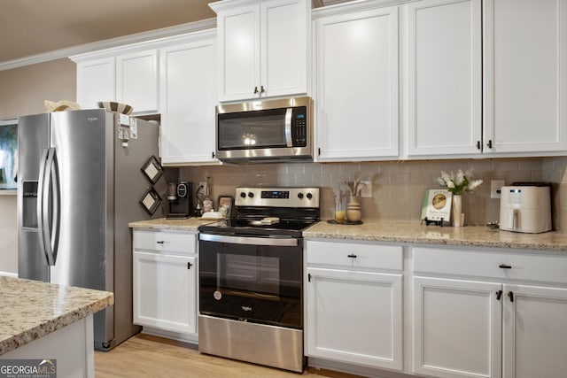 kitchen featuring white cabinetry, backsplash, light stone counters, and appliances with stainless steel finishes