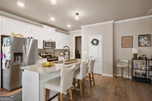 kitchen with sink, a breakfast bar area, a center island with sink, appliances with stainless steel finishes, and white cabinets