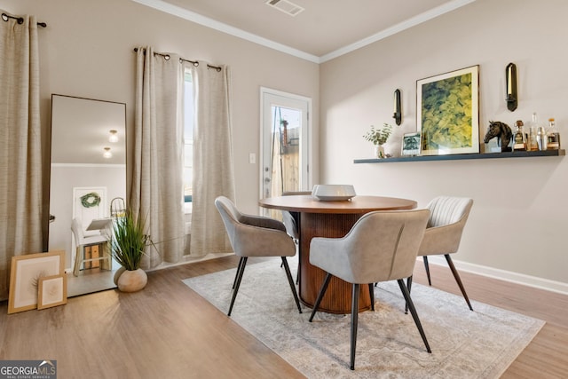 dining area with ornamental molding and light wood-type flooring