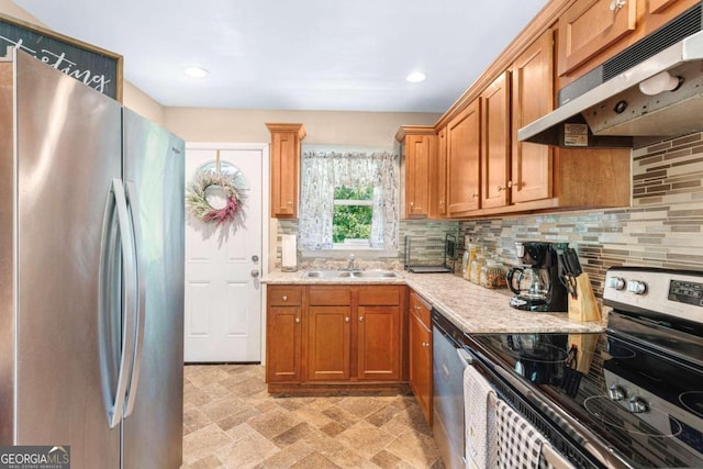 kitchen with light stone countertops, appliances with stainless steel finishes, backsplash, and sink