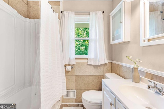 full bathroom featuring vanity, shower / bath combination with curtain, tile walls, and toilet