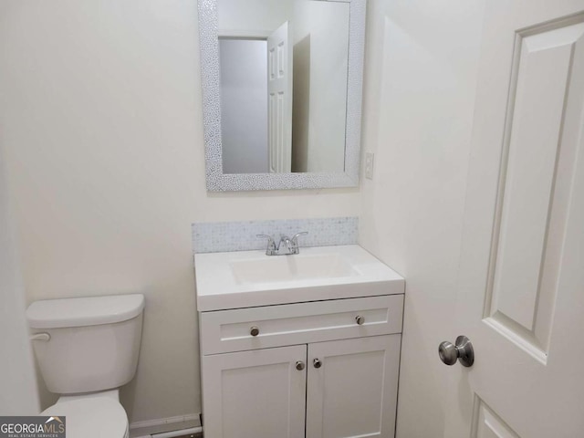 bathroom featuring vanity, toilet, and tasteful backsplash