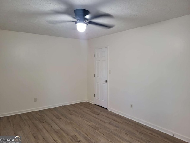 empty room with dark hardwood / wood-style floors, ceiling fan, and a textured ceiling