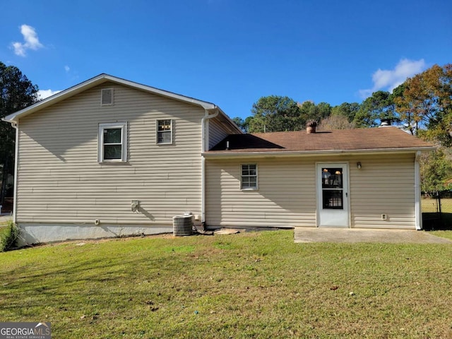 rear view of property featuring a lawn and cooling unit