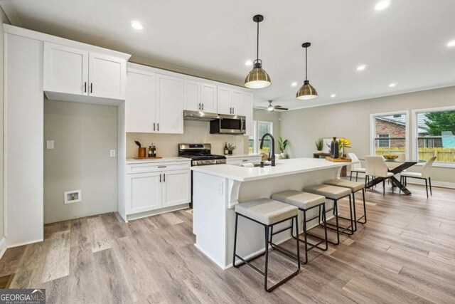 kitchen featuring white cabinets, appliances with stainless steel finishes, a kitchen island with sink, and ceiling fan