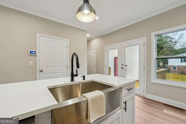 kitchen featuring sink, french doors, pendant lighting, white cabinets, and light wood-type flooring