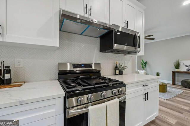 kitchen with decorative backsplash, white cabinetry, appliances with stainless steel finishes, and light hardwood / wood-style flooring