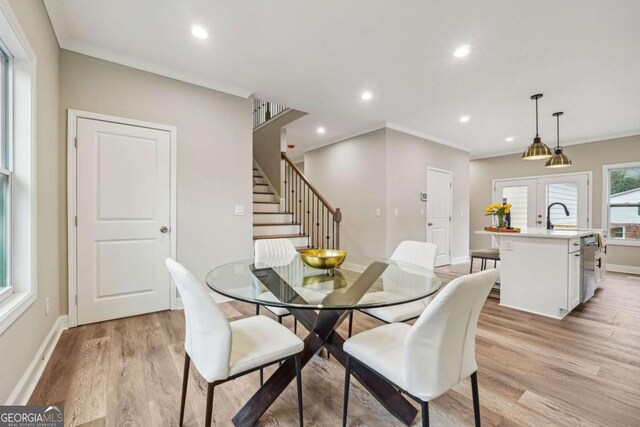 dining room with sink, french doors, light hardwood / wood-style floors, and ornamental molding