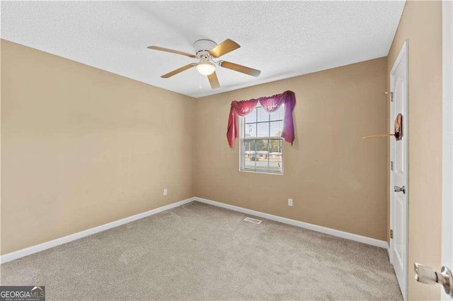 empty room featuring ceiling fan, light colored carpet, and a textured ceiling