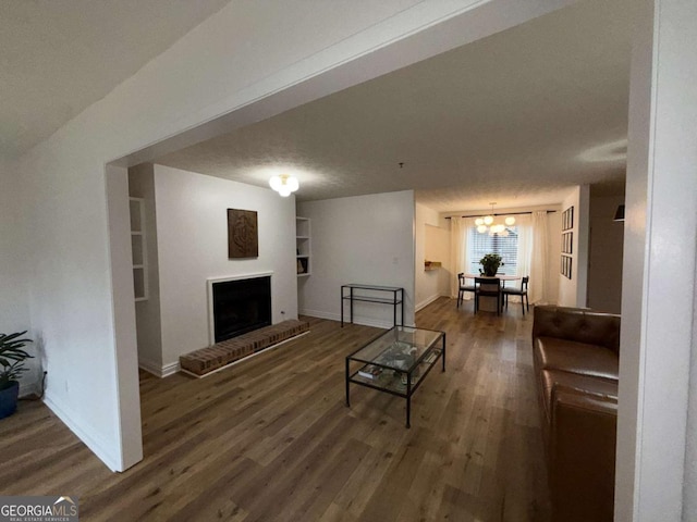 living room with a fireplace, a textured ceiling, built in features, and a notable chandelier