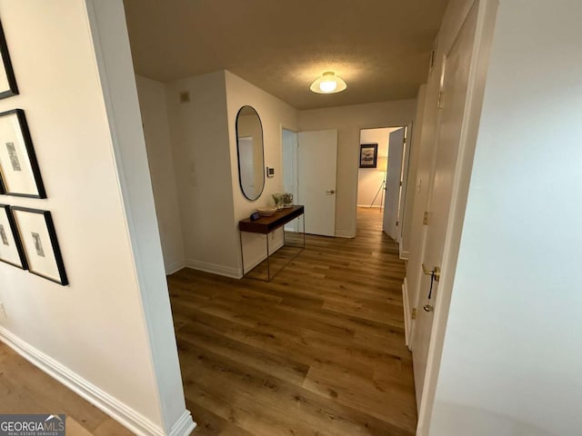 hallway with a textured ceiling and dark hardwood / wood-style flooring