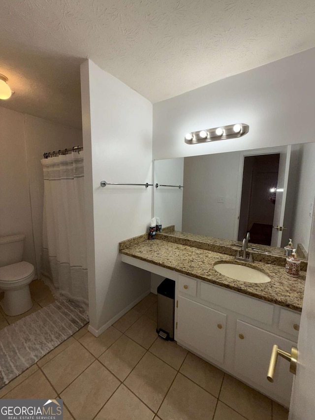 bathroom featuring tile patterned flooring, a textured ceiling, vanity, and toilet