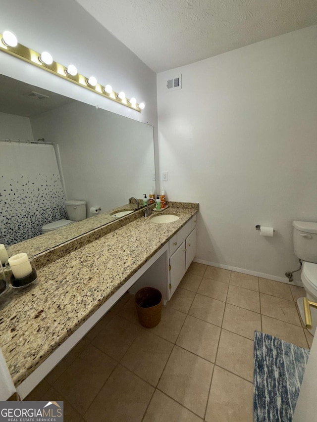 bathroom featuring tile patterned floors, vanity, toilet, and a textured ceiling