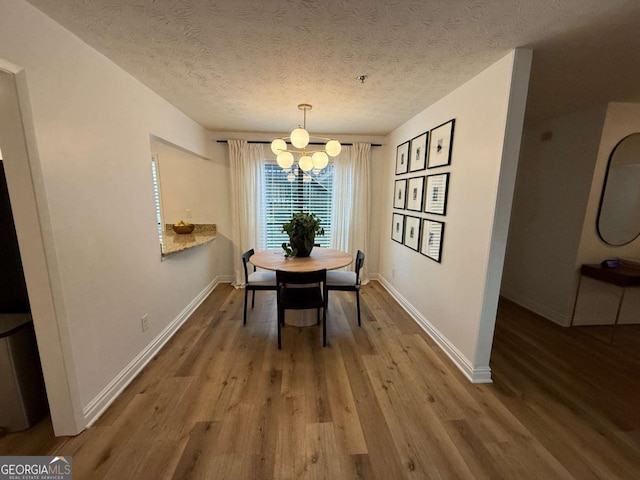 dining area with a textured ceiling, hardwood / wood-style flooring, and a notable chandelier