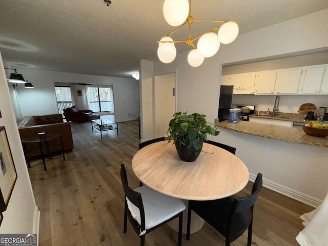 dining room with an inviting chandelier, sink, and dark wood-type flooring