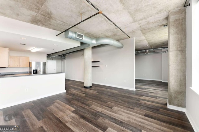 basement with dark wood-type flooring and stainless steel refrigerator with ice dispenser