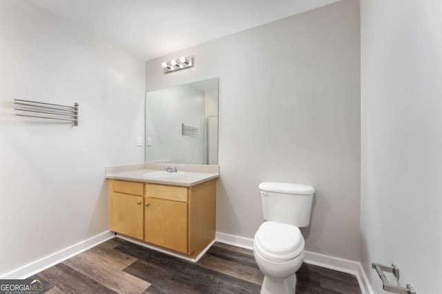 bathroom with hardwood / wood-style floors, vanity, and toilet