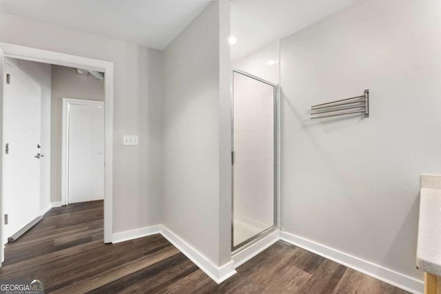 bathroom with hardwood / wood-style flooring and a shower with shower door