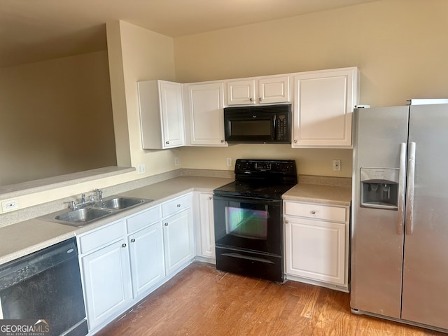 kitchen with light hardwood / wood-style flooring, white cabinets, black appliances, and sink