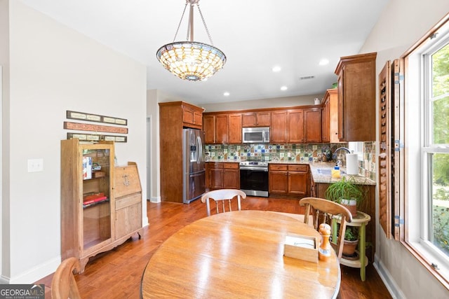 kitchen featuring pendant lighting, sink, decorative backsplash, a notable chandelier, and stainless steel appliances