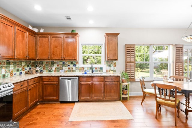 kitchen with light stone countertops, sink, decorative backsplash, appliances with stainless steel finishes, and light wood-type flooring